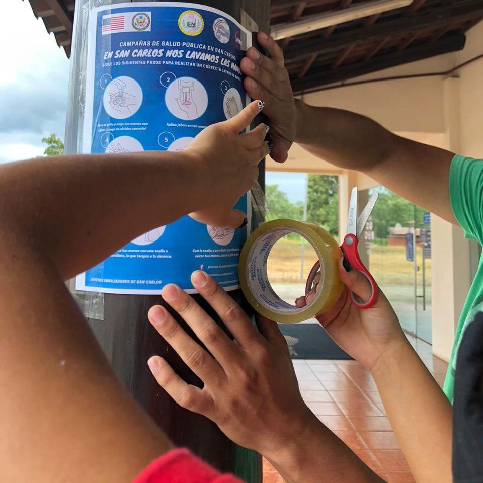 Hands pasting a flyer on a post