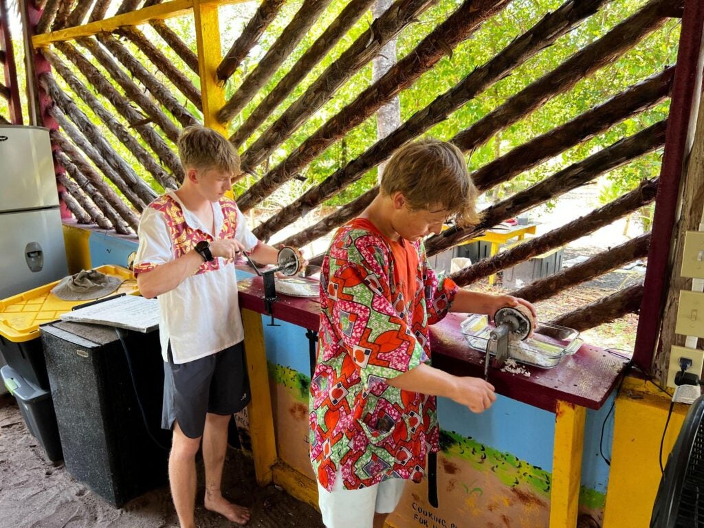 JT and Will work hard to grind the coconut for hudut, a staple dish of the Garifuna culture. 